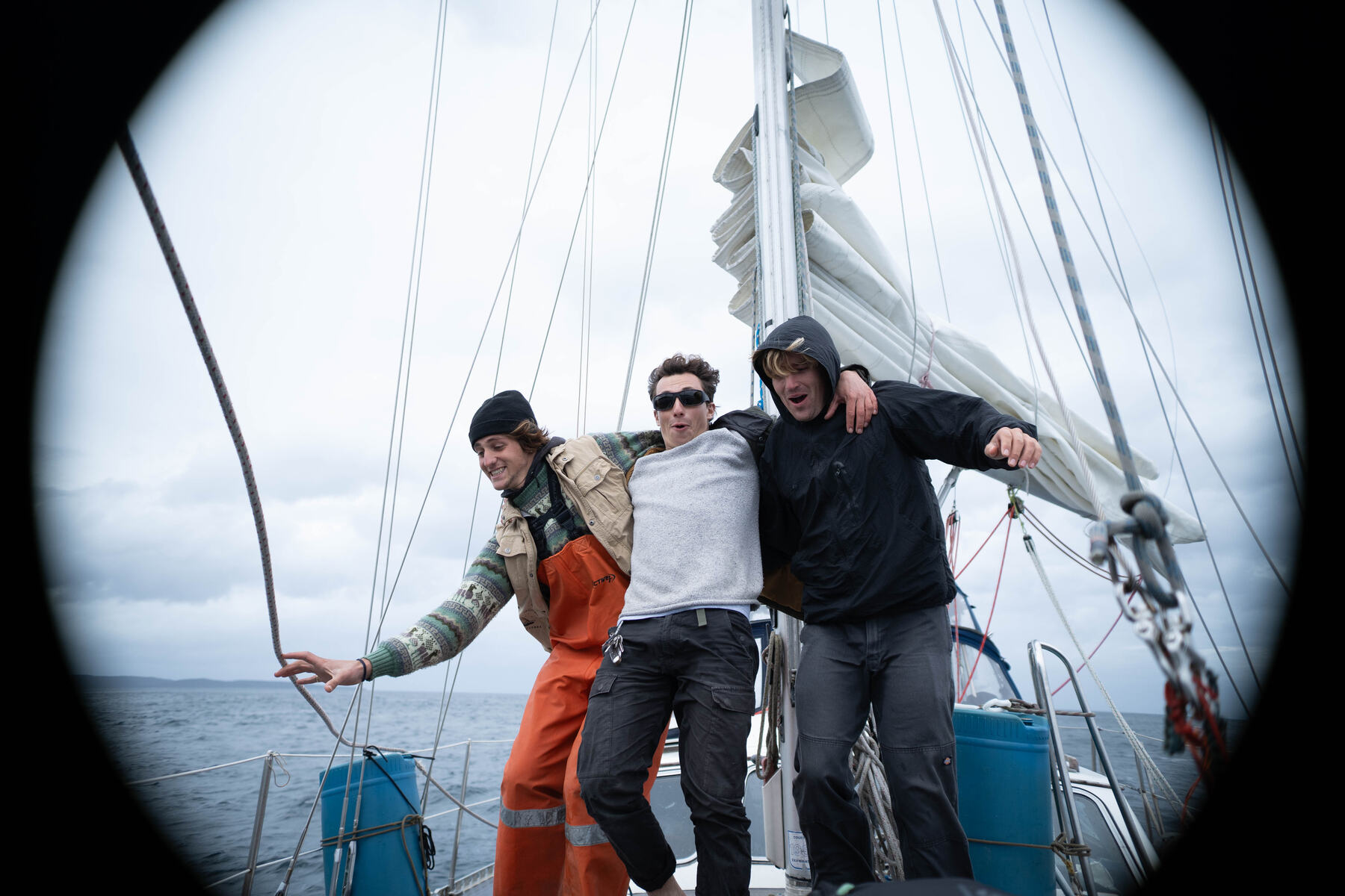 Tres tripulantes abrazados en la proa del velero