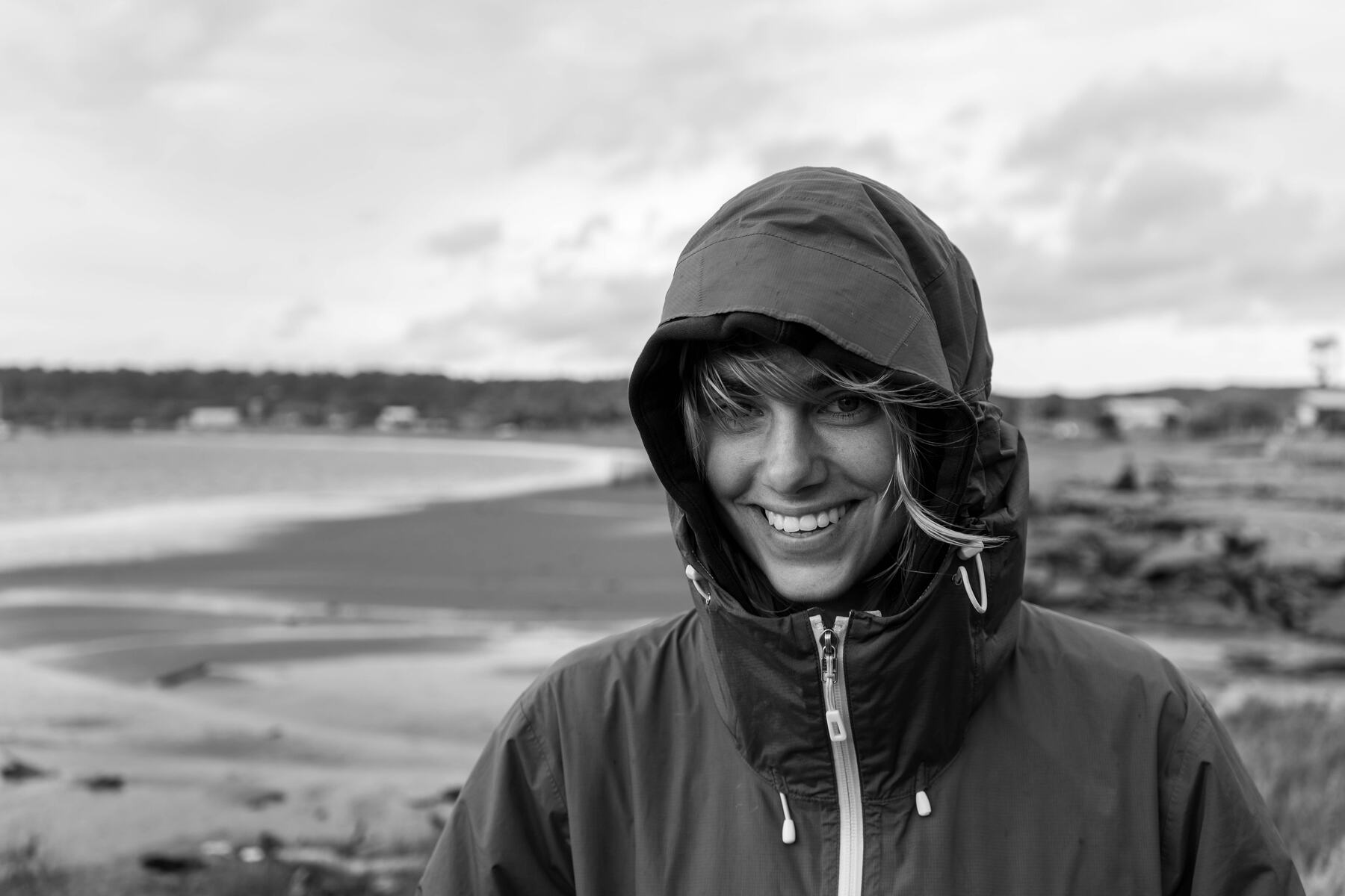 Viajera sonriendo con capucha en la playa