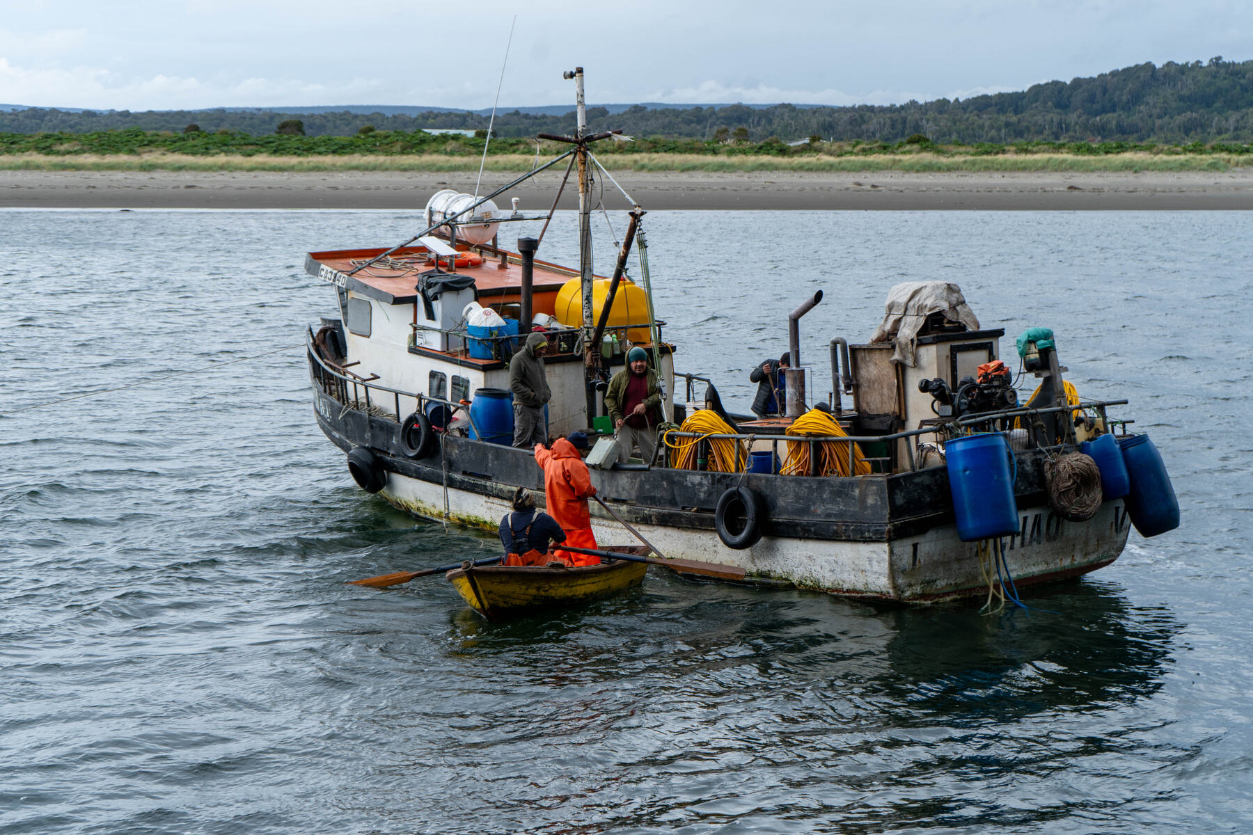 Lancha de pesca artesanal de colores con un pescador remando en un bote