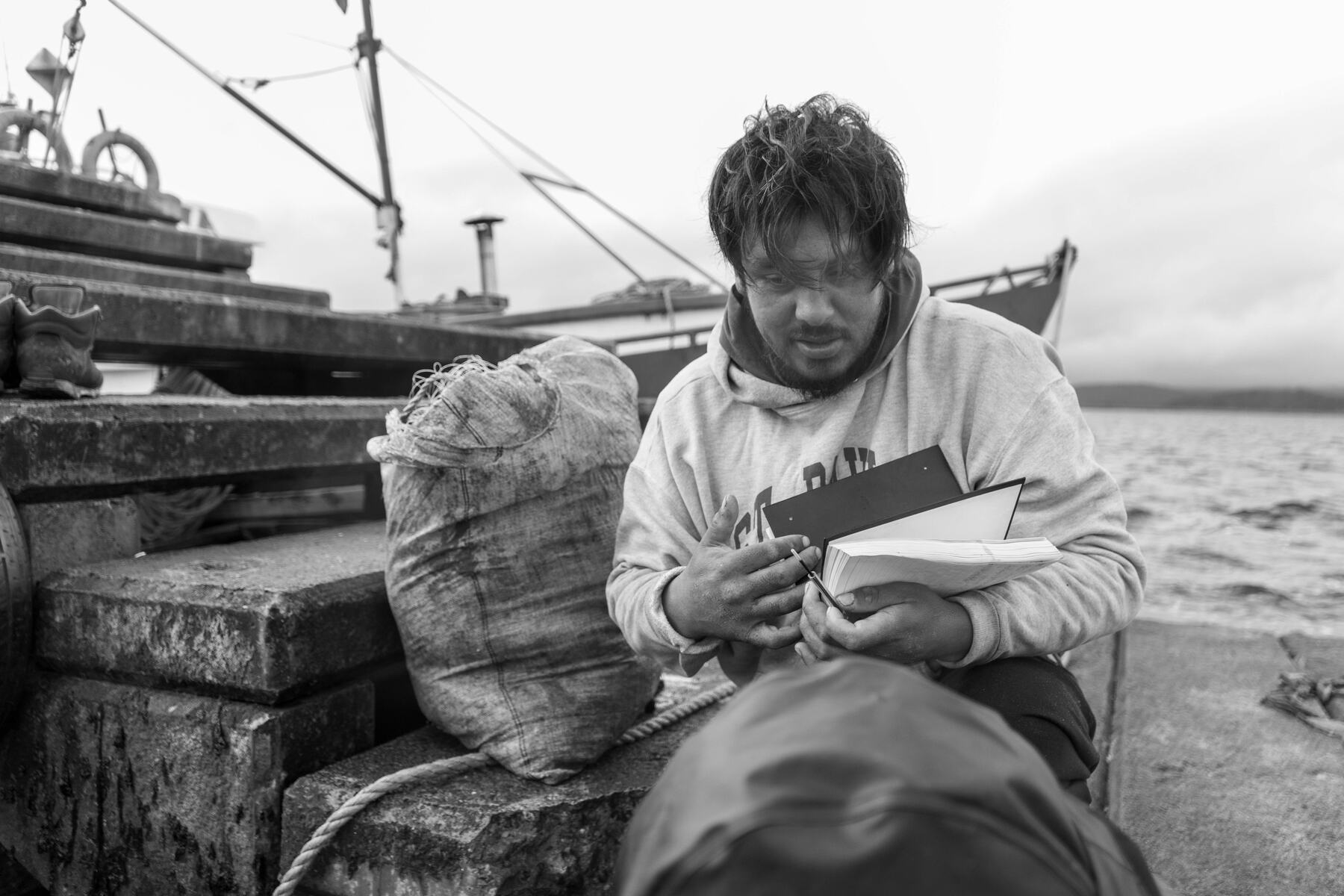 Pescador revisando papeles junto a su lancha